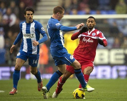 Wigan Athletic's James McCarthy (C) fights for the ball against Queens Park Rangers' Armand Traore (R)